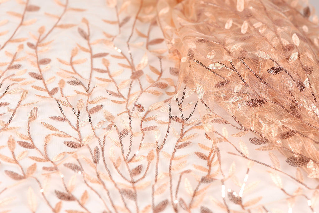 a close-up view of a fabric with a delicate, intricate floral pattern. The fabric appears to be made of a light-colored material, possibly silk or chiffon, with a subtle, shimmering texture. The pattern consists of numerous small, thin, and delicate leaves and branches, creating a visually appealing and delicate design.