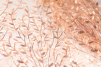a close-up view of a fabric with a delicate, intricate floral pattern. The fabric appears to be made of a light-colored material, possibly silk or chiffon, with a subtle, shimmering texture. The pattern consists of numerous small, thin, and delicate leaves and branches, creating a visually appealing and delicate design.