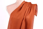 a mannequin wearing a red, draped fabric draped over its shoulder.