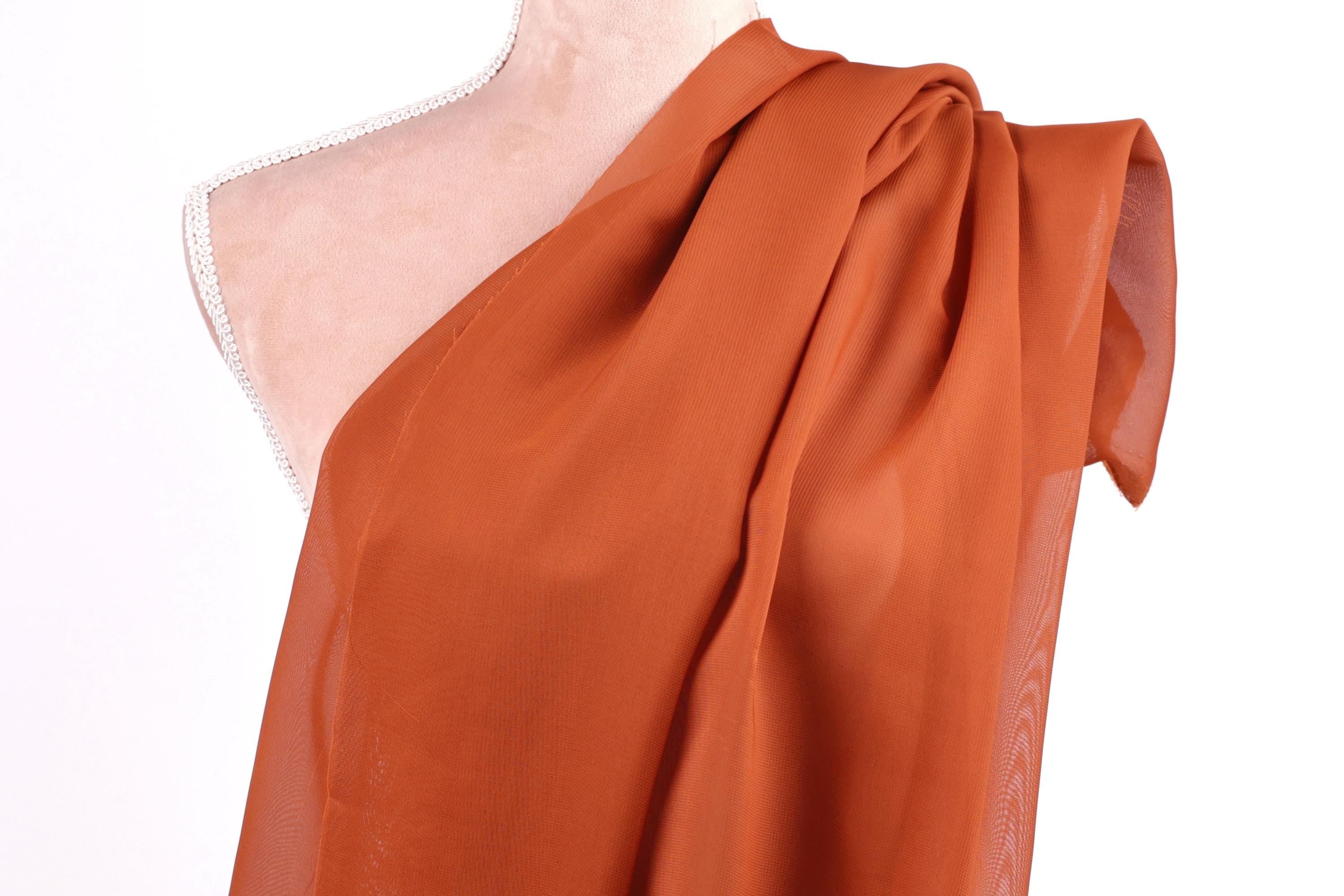 a mannequin wearing a red, draped fabric draped over its shoulder.