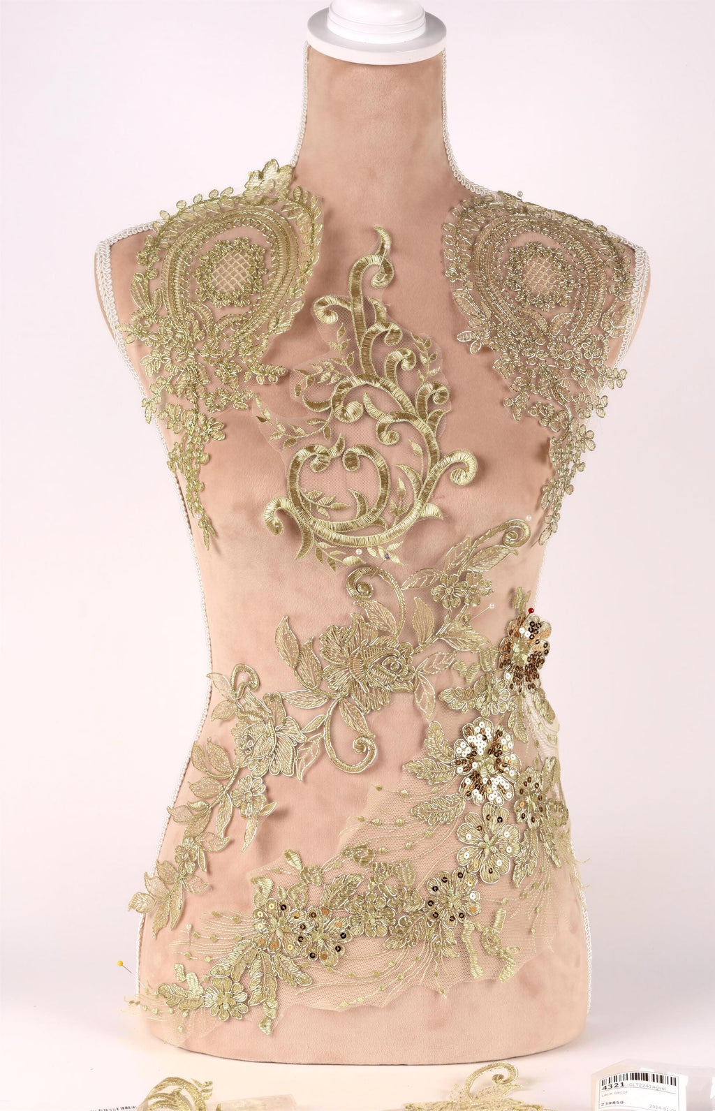 A mannequin with a beige body and gold embroidered details, including floral and leaf patterns, as well as sequin accents.
