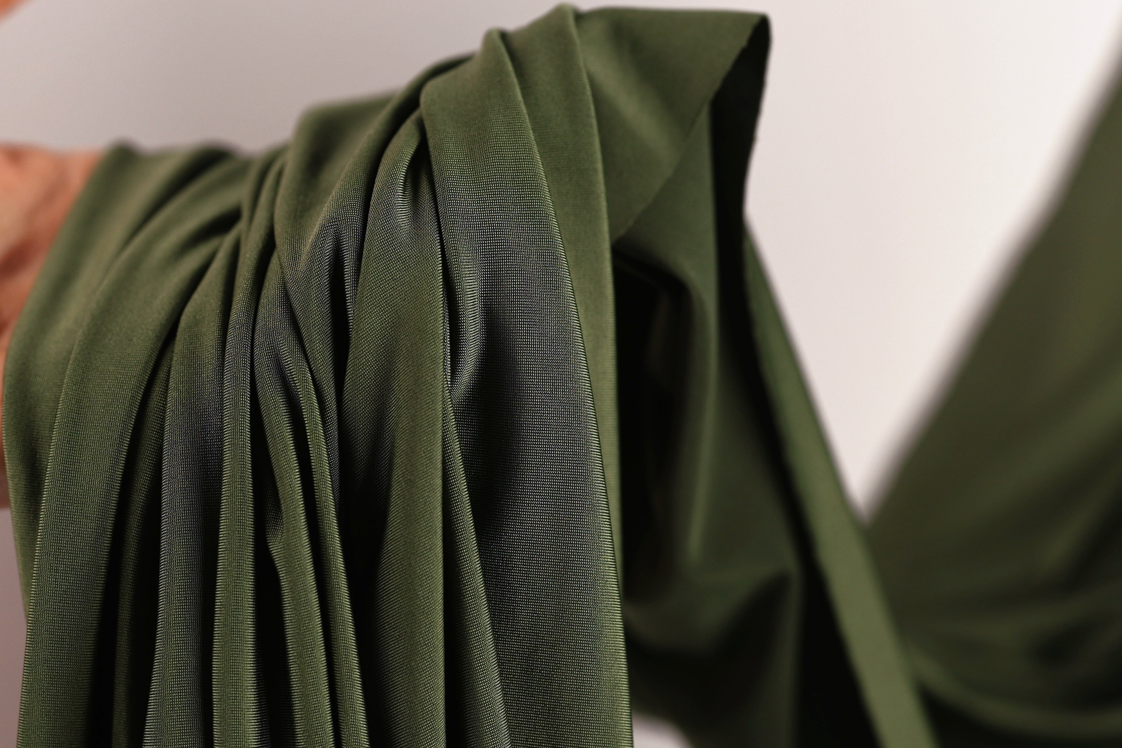 A close-up view of a green fabric, possibly a piece of clothing or a textile, with a blurred background.