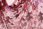 a close-up view of a fabric with a floral pattern in shades of red and pink. The fabric appears to be made of a sheer material, with a delicate and intricate design. The pattern consists of various shades of red and pink flowers and leaves, creating a visually striking and vibrant appearance.