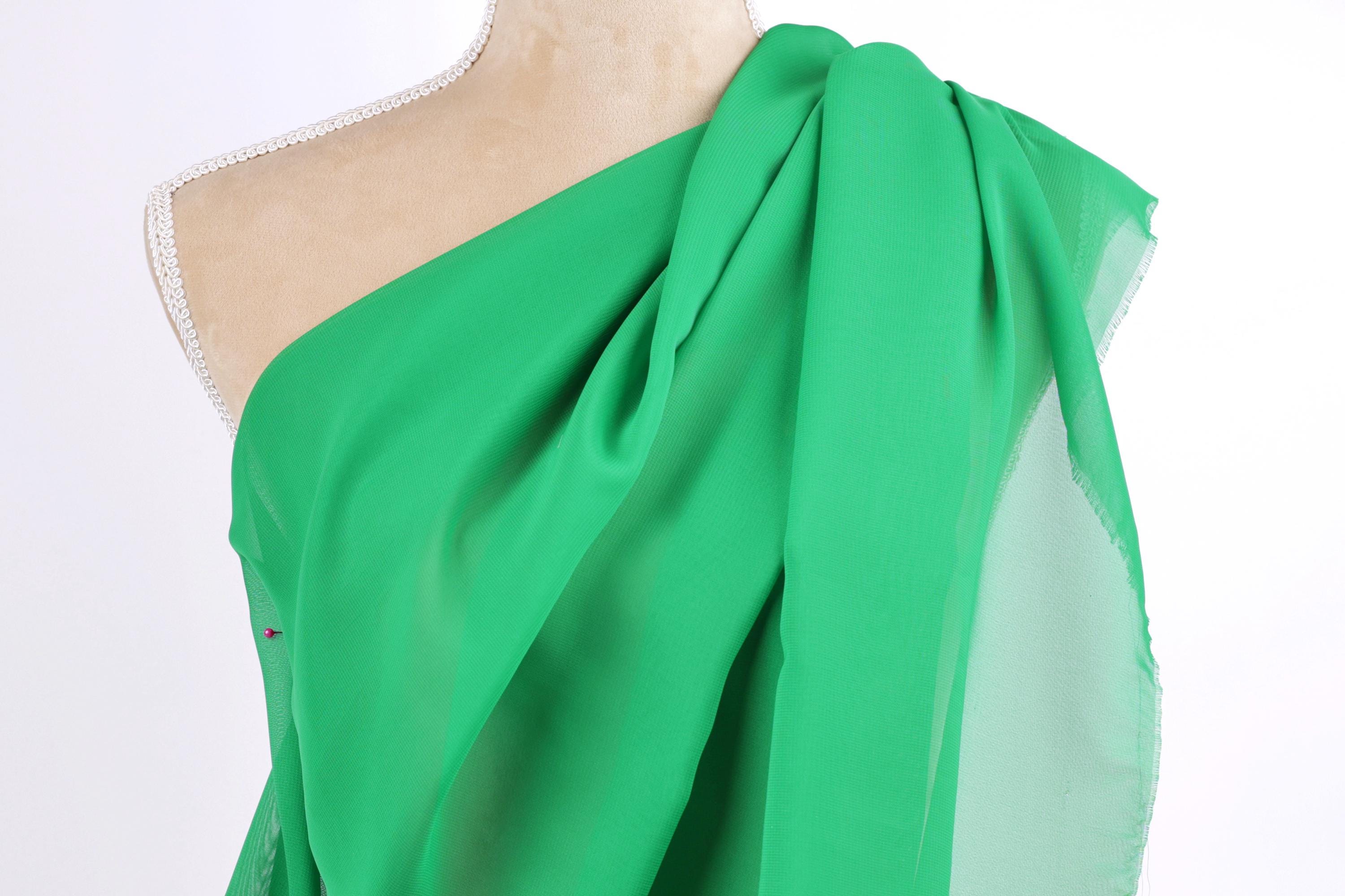 A mannequin wearing a green one-shoulder dress with a draped, flowing fabric.