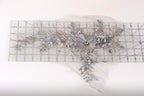 a decorative silver floral piece with intricate details, including leaves, flowers, and a central flower, all set against a white background.