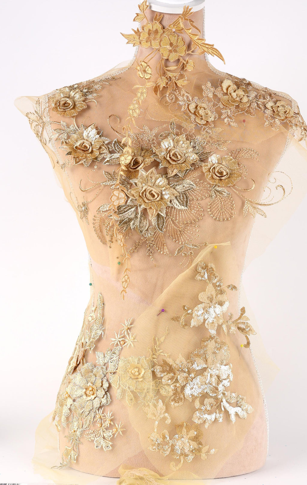 A mannequin wearing a beige dress with intricate gold floral embroidery and lace details.