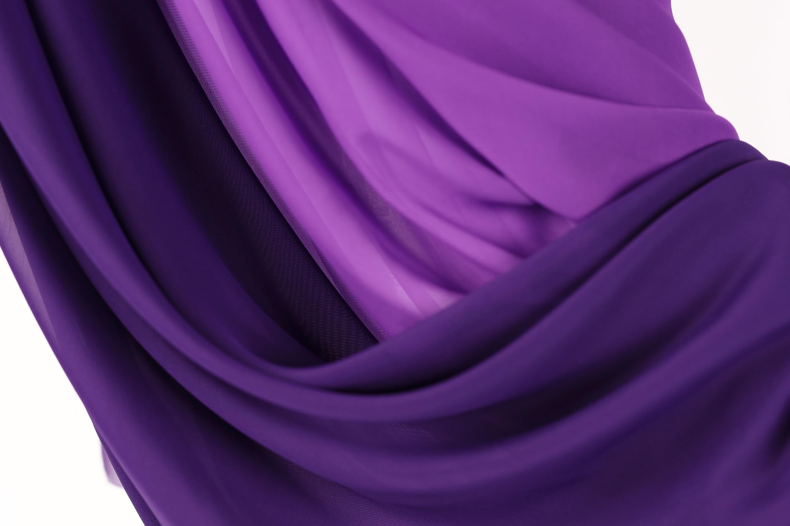 The image is a close-up of a fabric with a purple and blue color scheme, featuring a soft, flowing texture.