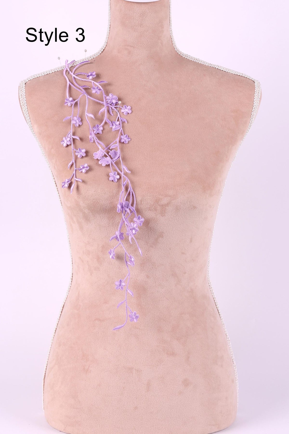 A mannequin with a floral necklace draped across its shoulder.