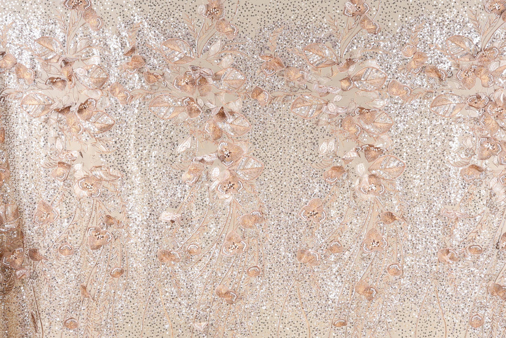 a close-up view of a fabric with a floral pattern, including leaves and flowers. The fabric appears to be made of a shiny, glittery material, giving it a sparkly and elegant appearance.