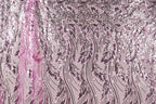 a close-up view of a fabric with a repeating pattern of pink and black sequin designs. The pattern consists of various shapes and sizes of sequins arranged in a diagonal line across the fabric, creating a visually striking and intricate design.