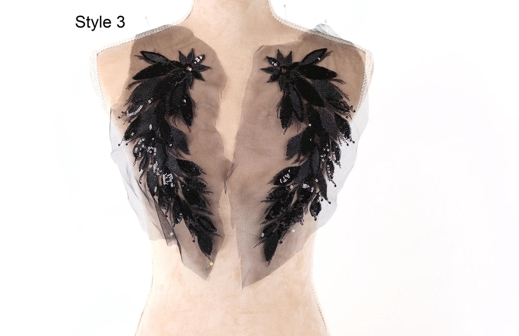 a mannequin with a unique design on its bust, consisting of two large black feathers with intricate black and silver embellishments.