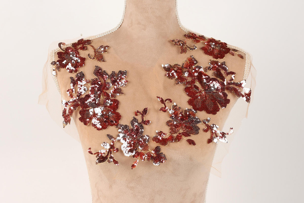 A mannequin torso with a beige fabric adorned with red and silver sequin flowers.