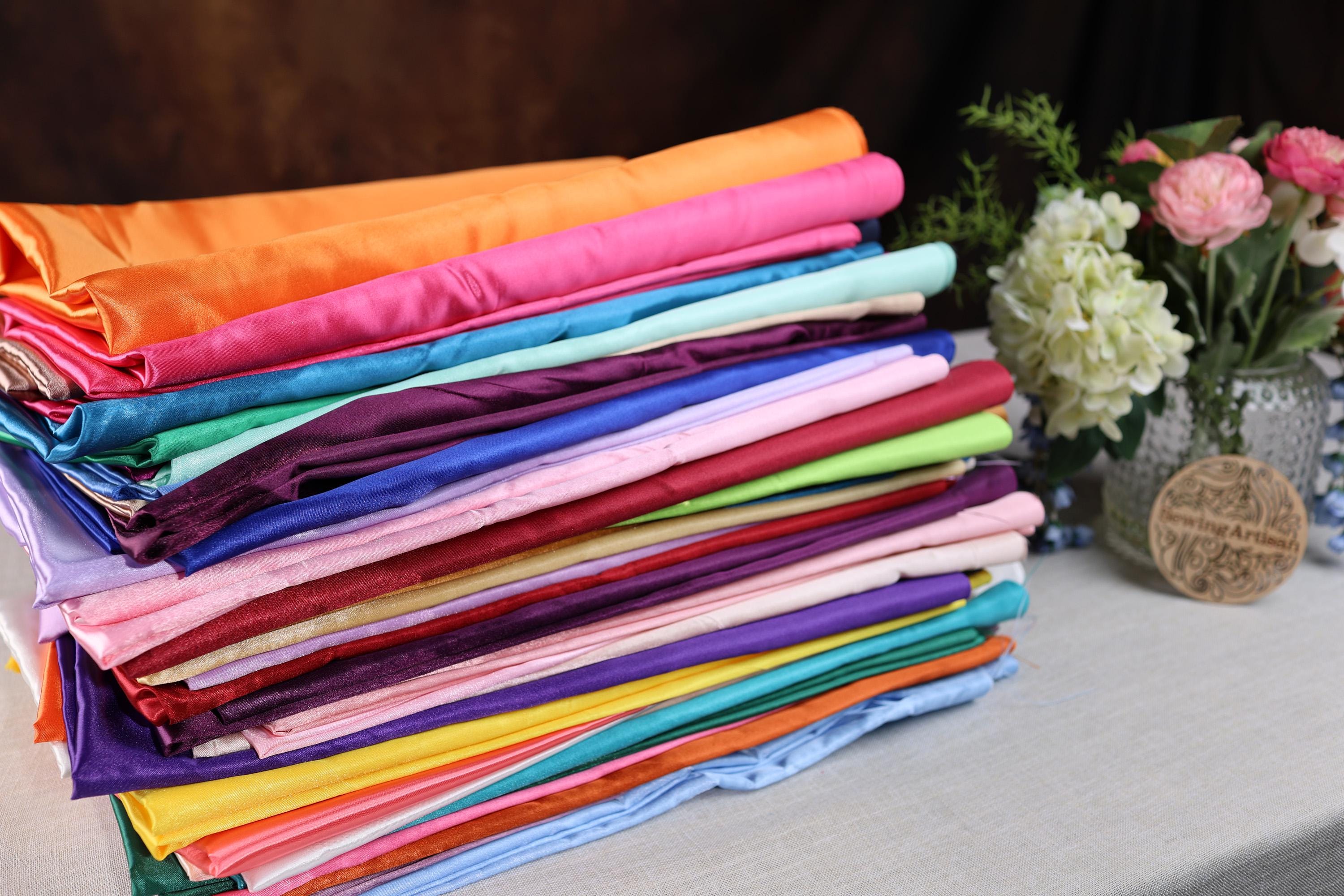 a stack of folded cloths sitting on a table next to a vase of flowers