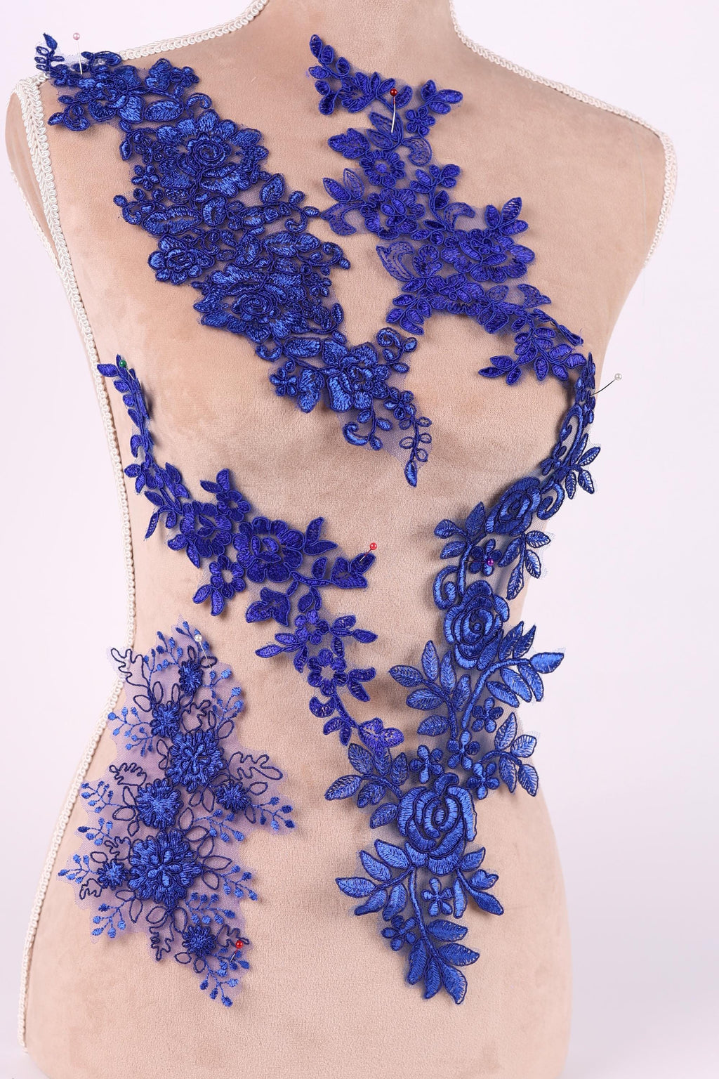 A mannequin torso wearing a dress with a blue floral lace overlay.