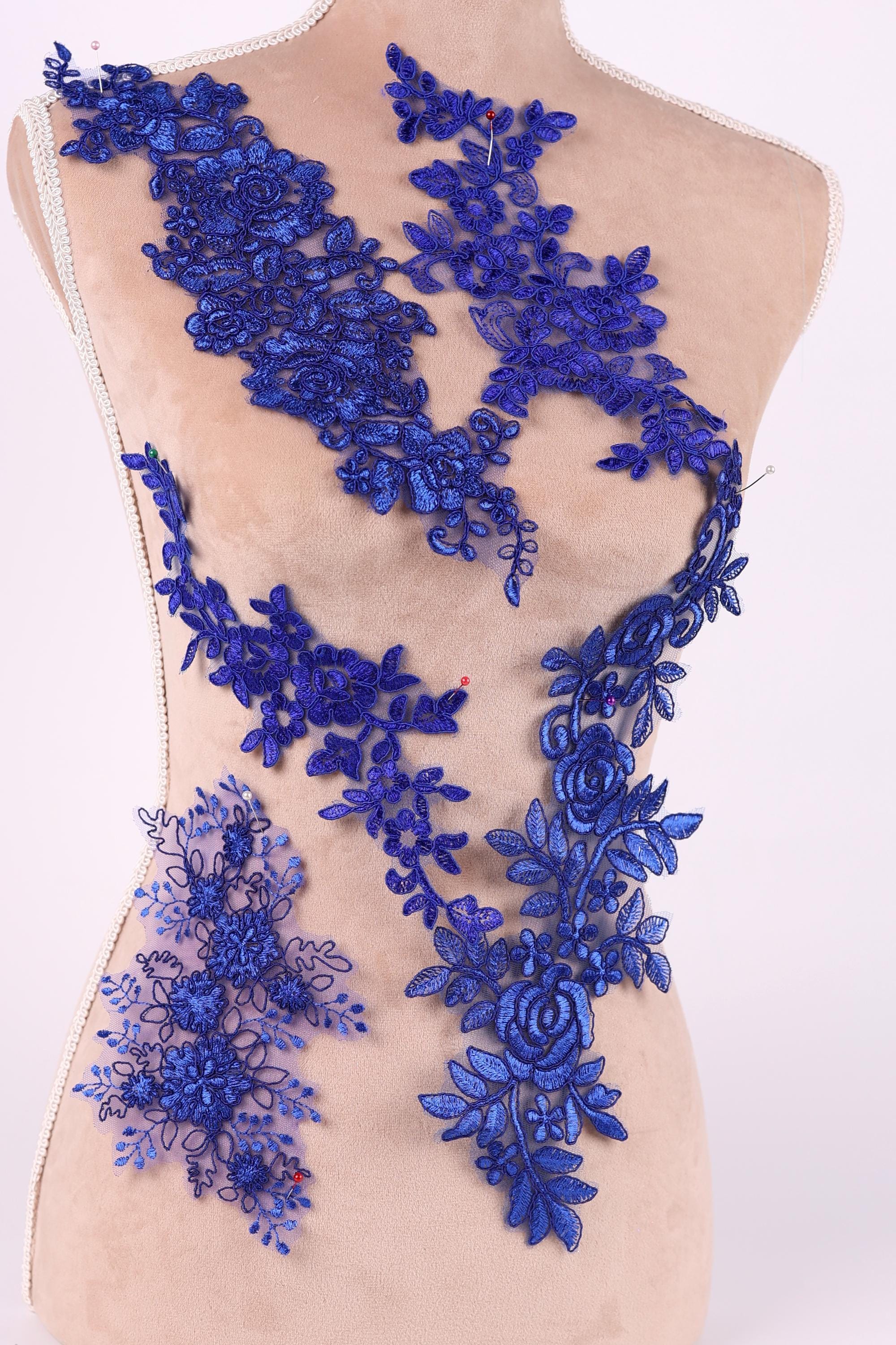 A mannequin torso wearing a dress with a blue floral lace overlay.