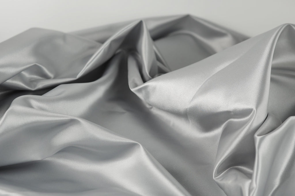 a close-up view of a crumpled, shiny, and textured fabric, possibly silver or gray in color.