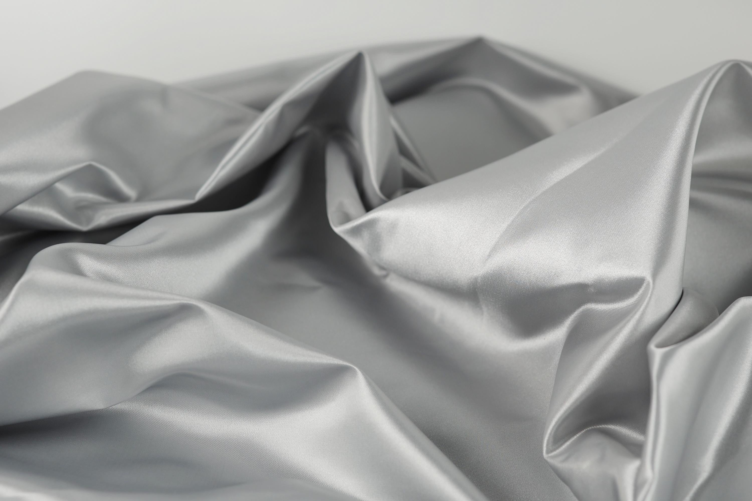 a close-up view of a crumpled, shiny, and textured fabric, possibly silver or gray in color.