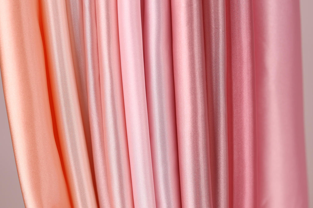 a close-up view of a collection of fabric swatches in various shades of pink, ranging from light to dark.