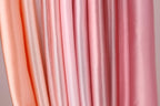 a close-up view of a collection of fabric swatches in various shades of pink, ranging from light to dark.