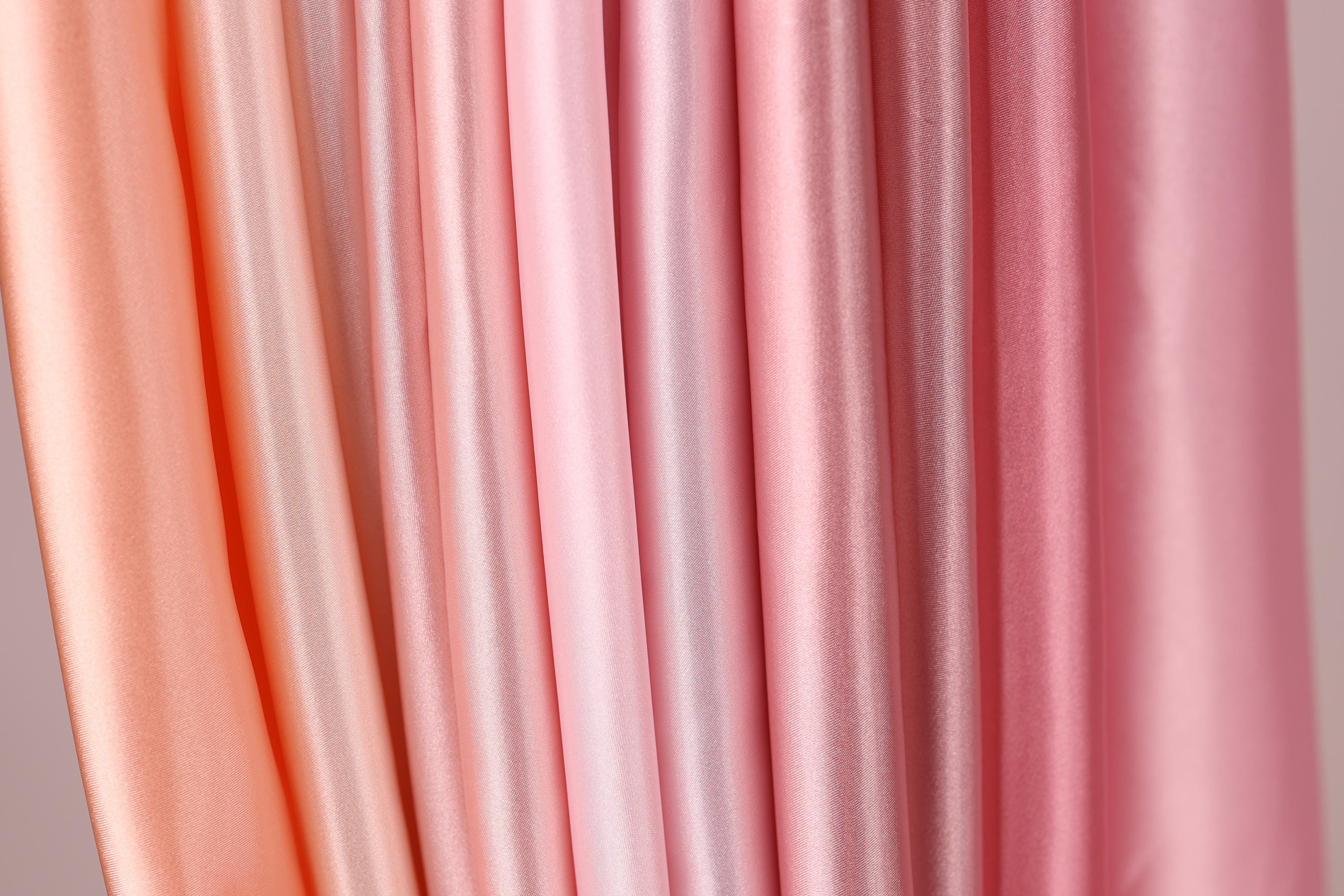 a close-up view of a collection of fabric swatches in various shades of pink, ranging from light to dark.