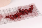 a clear ruler with red sequin flowers printed on it.