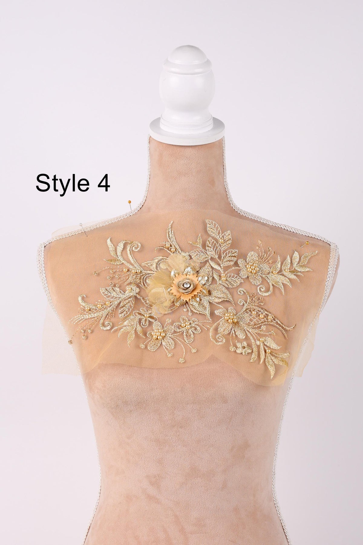 A mannequin with a decorative fabric piece on its back, featuring a floral design with gold and white elements.