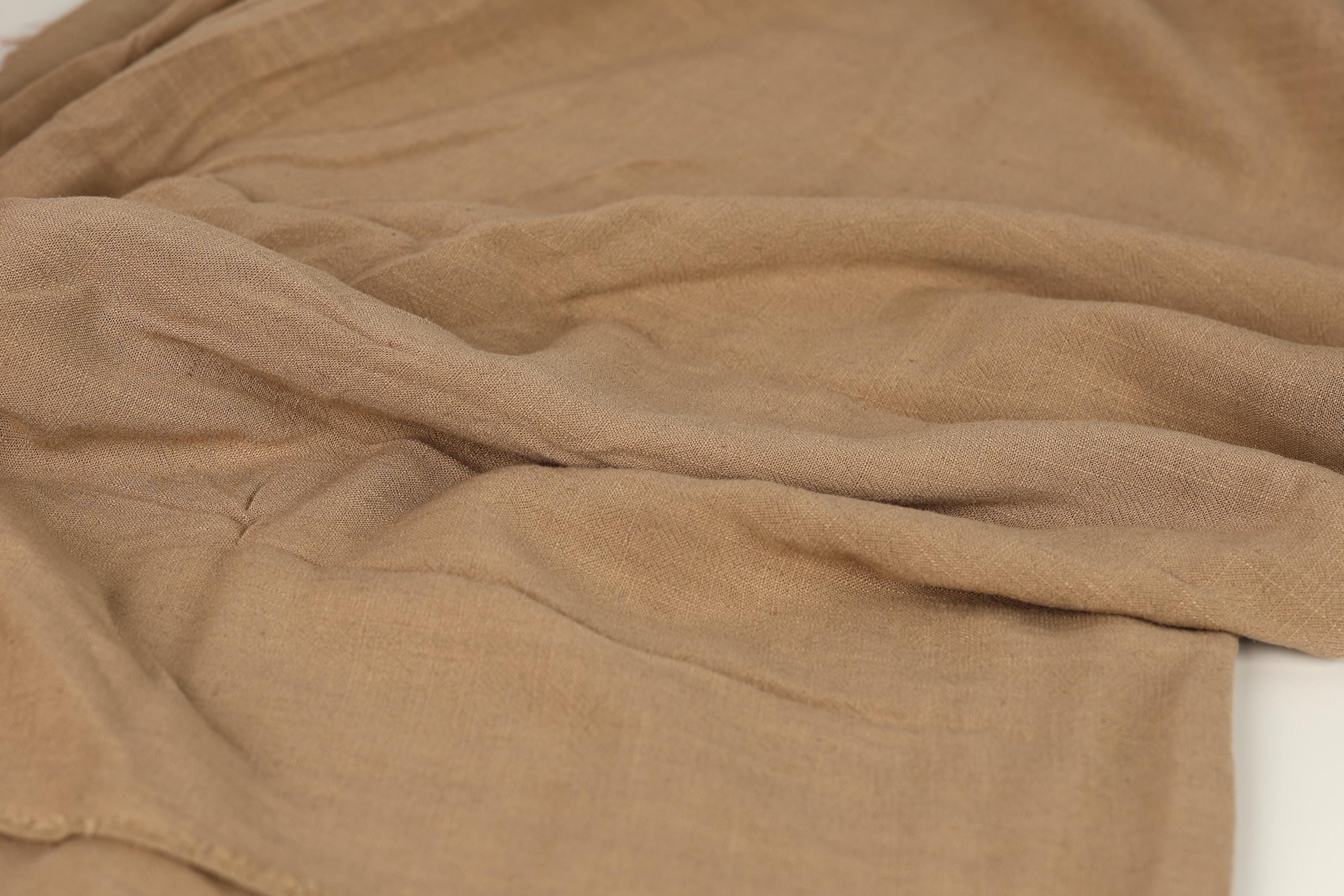 A close-up image of a crumpled, beige-colored fabric, possibly a piece of clothing or a textile.