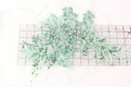 a collection of green floral embroidery pieces, including flowers and leaves, arranged on a ruler for scale.