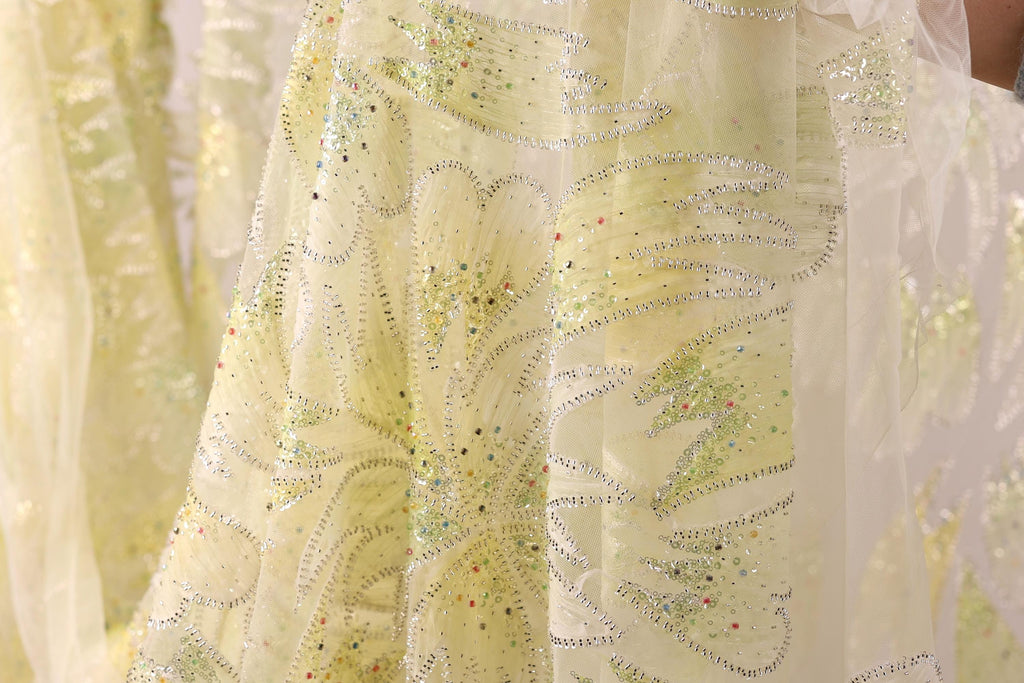 a close-up view of a yellow fabric with a floral pattern and sequin embellishments.