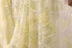 a close-up view of a yellow fabric with a floral pattern and sequin embellishments.