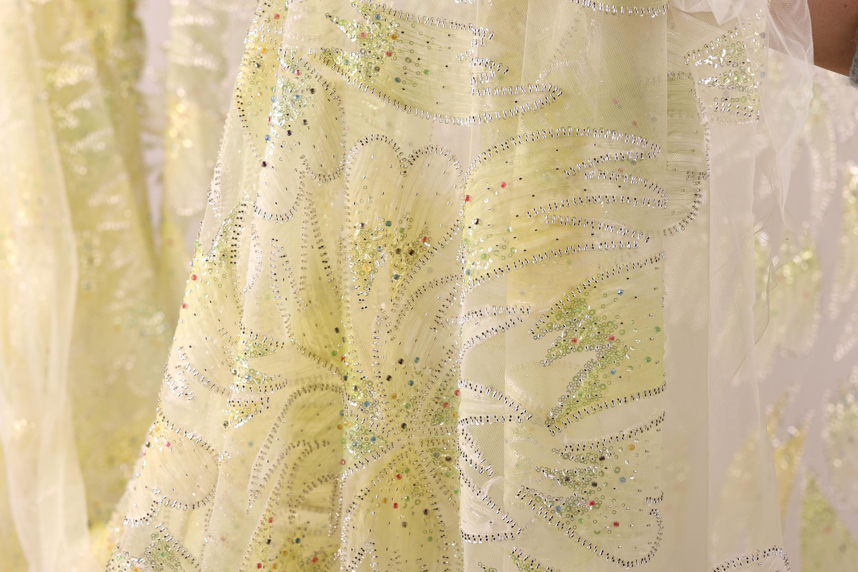 a close-up view of a yellow fabric with a floral pattern and sequin embellishments.