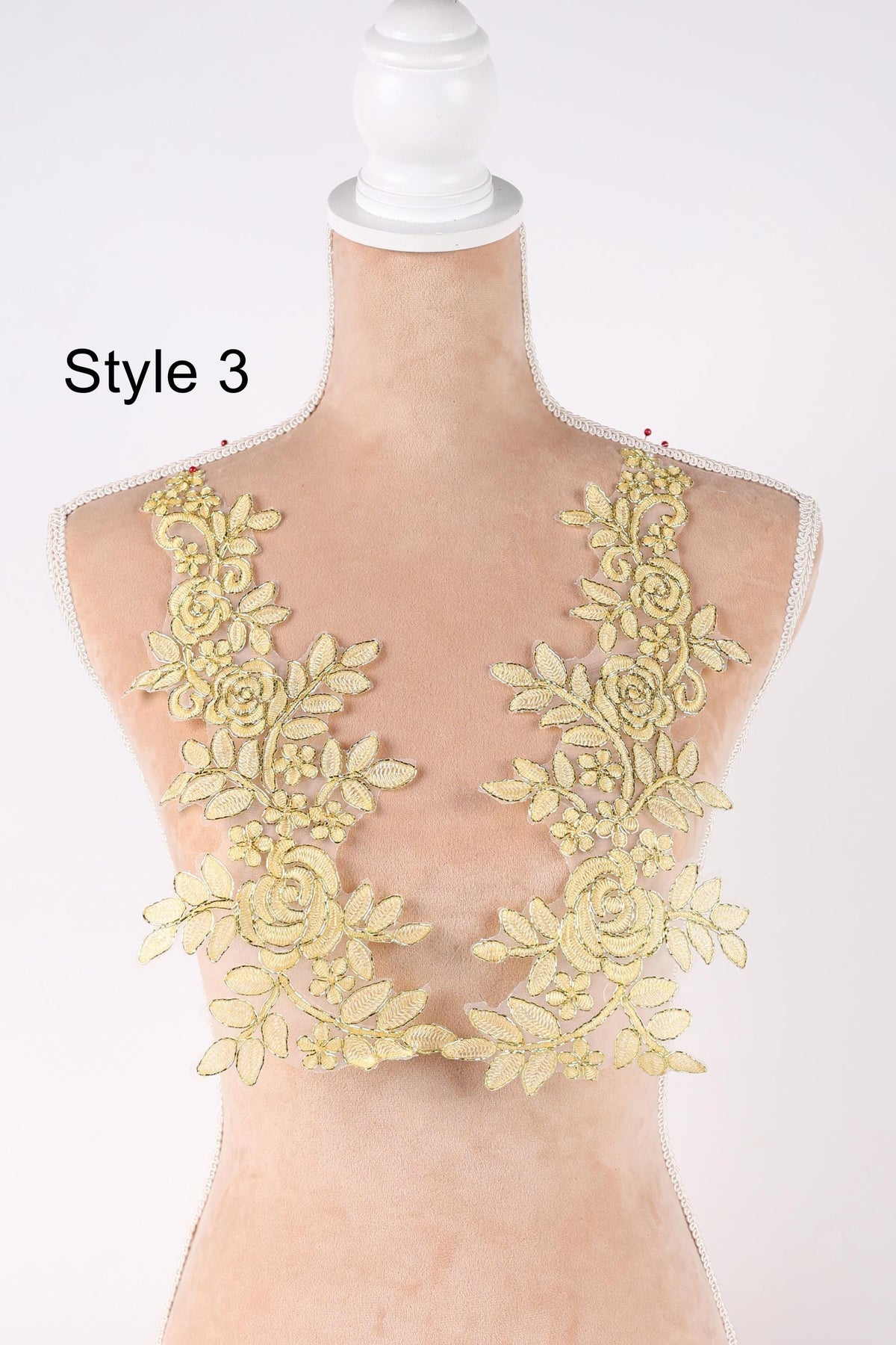 A mannequin wearing a dress with yellow floral lace appliques on the shoulders.