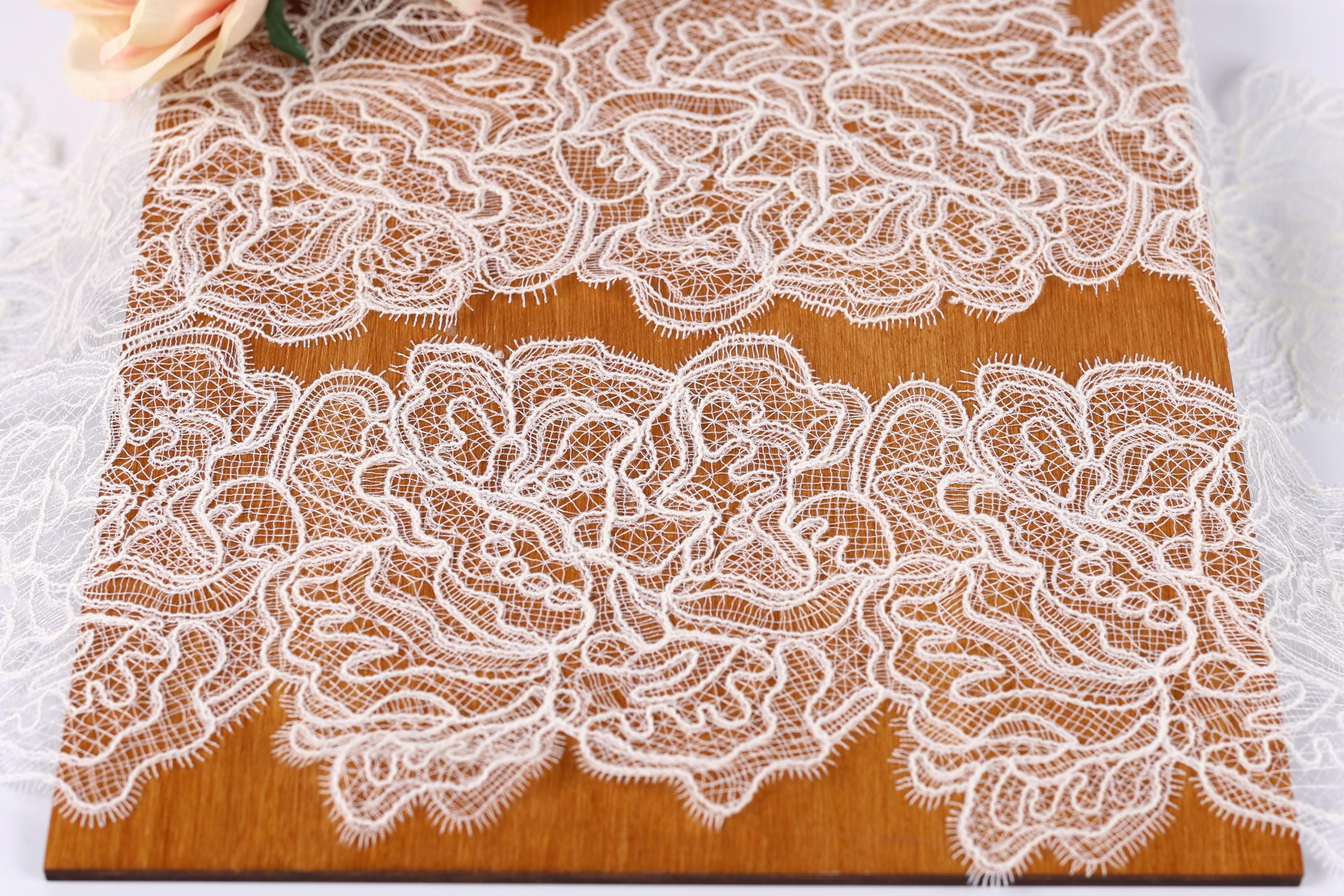 a close-up view of a wooden surface adorned with intricate white lace patterns. The lace appears to be hand-stitched and has a delicate, ornate design. The wooden surface is positioned in the center of the image, drawing attention to the lace patterns. The background is blurred, keeping the focus on the lace and the wooden surface.
