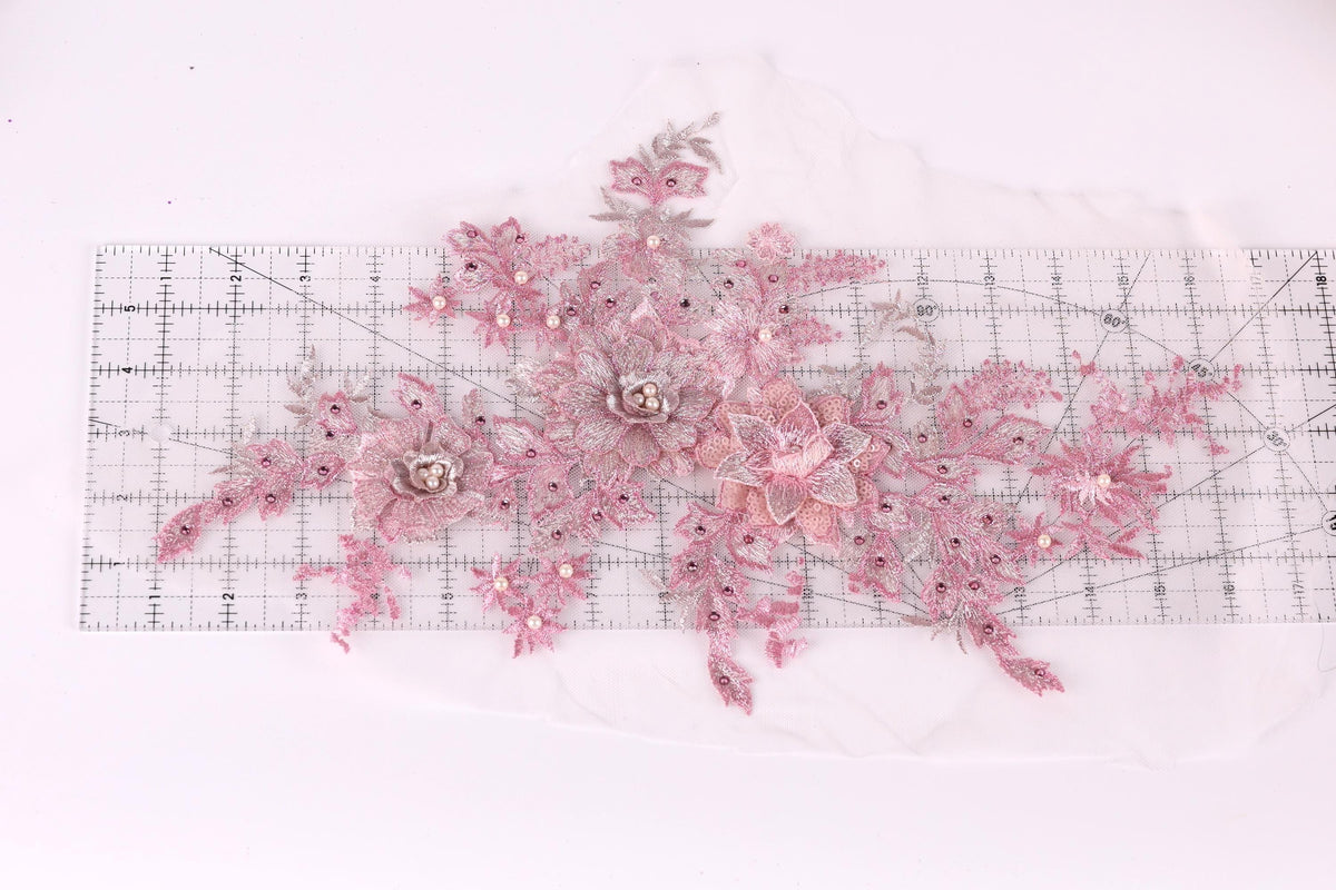 a collection of pink and white floral designs, including flowers and leaves, arranged on a transparent ruler.