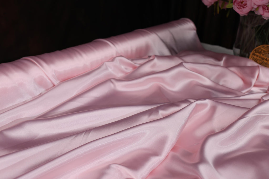 a vase of pink flowers sitting on top of a bed