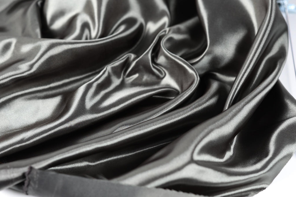 a close-up view of a shiny, silky-looking fabric, possibly satin or silk, with a smooth and flowing texture.