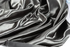 a close-up view of a shiny, silky-looking fabric, possibly satin or silk, with a smooth and flowing texture.