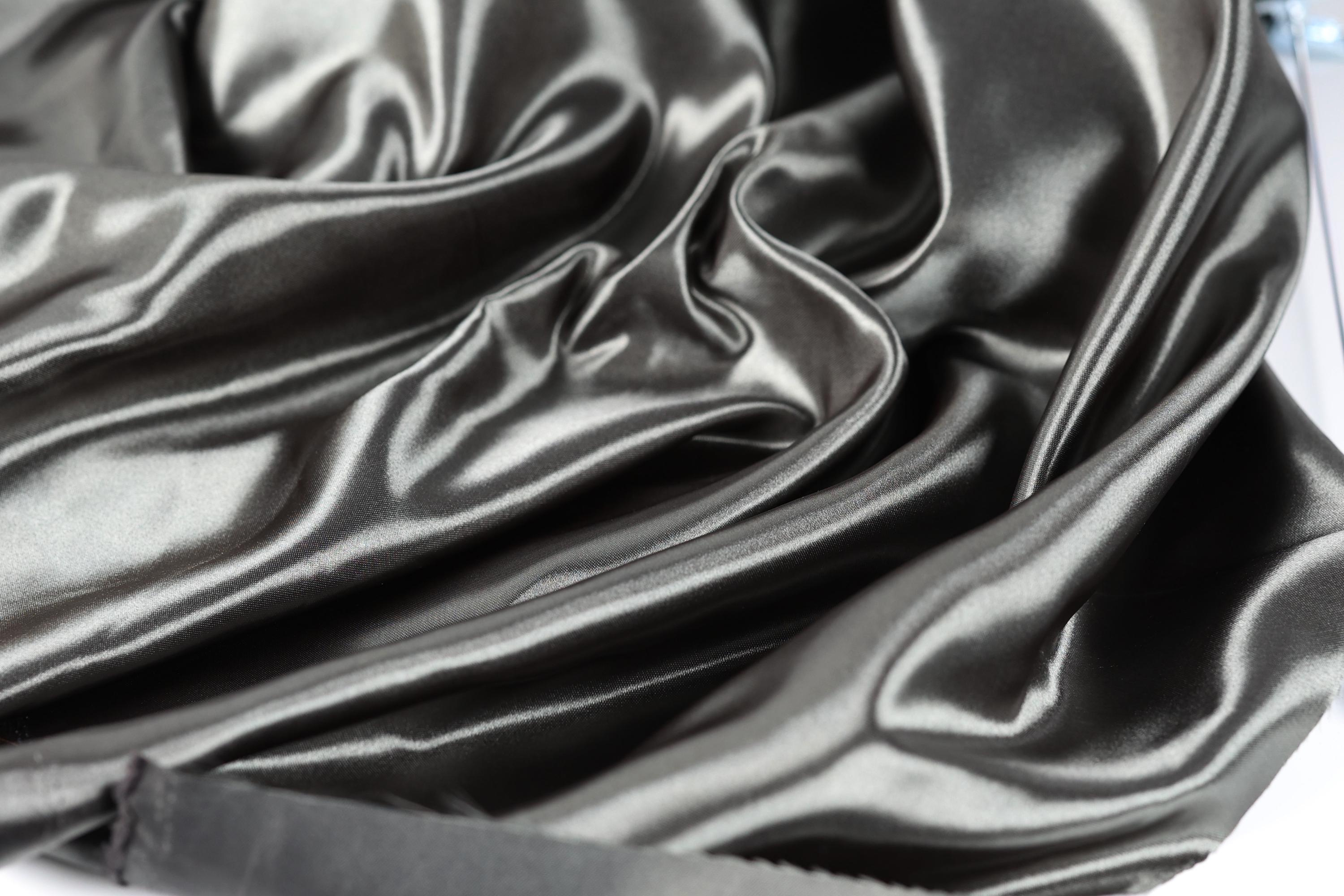 a close-up view of a shiny, silky-looking fabric, possibly satin or silk, with a smooth and flowing texture.