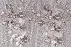 The image is a close-up of a fabric with a floral pattern, featuring a variety of leaves and flowers in shades of gray and white. The pattern is intricate and detailed, with the leaves and flowers arranged in a visually appealing manner. The background of the image is a light gray color, which contrasts with the darker tones of the floral pattern. The overall composition of the image is balanced and harmonious, with the floral pattern taking center stage.