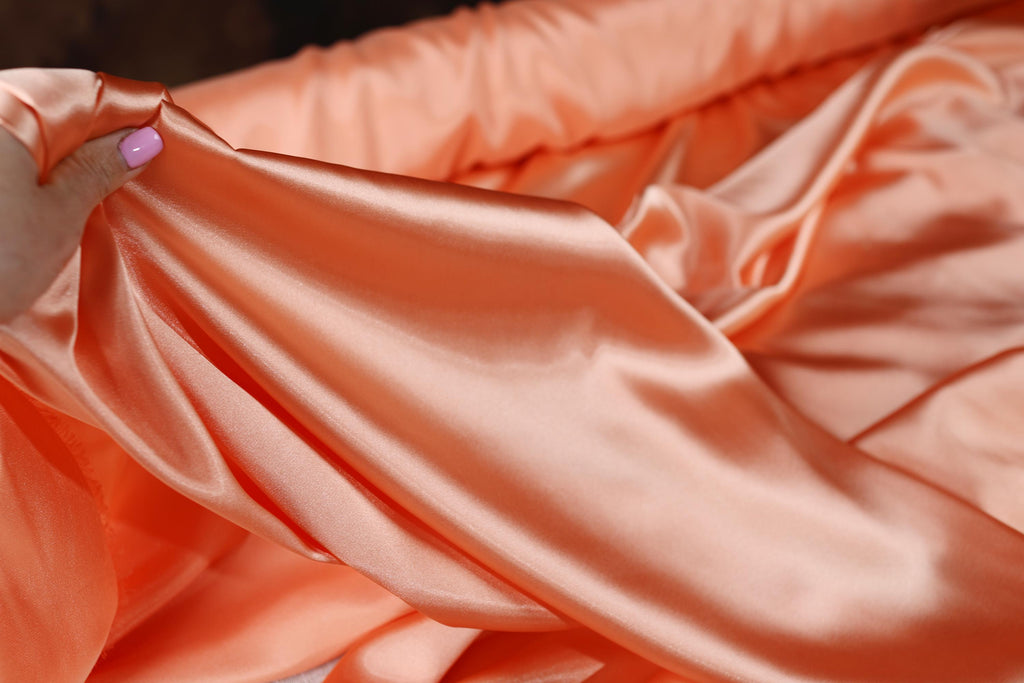 a woman in a pink dress is holding a pink satin material