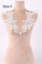 A mannequin wearing a beige dress with a white lace collar and floral embellishments.