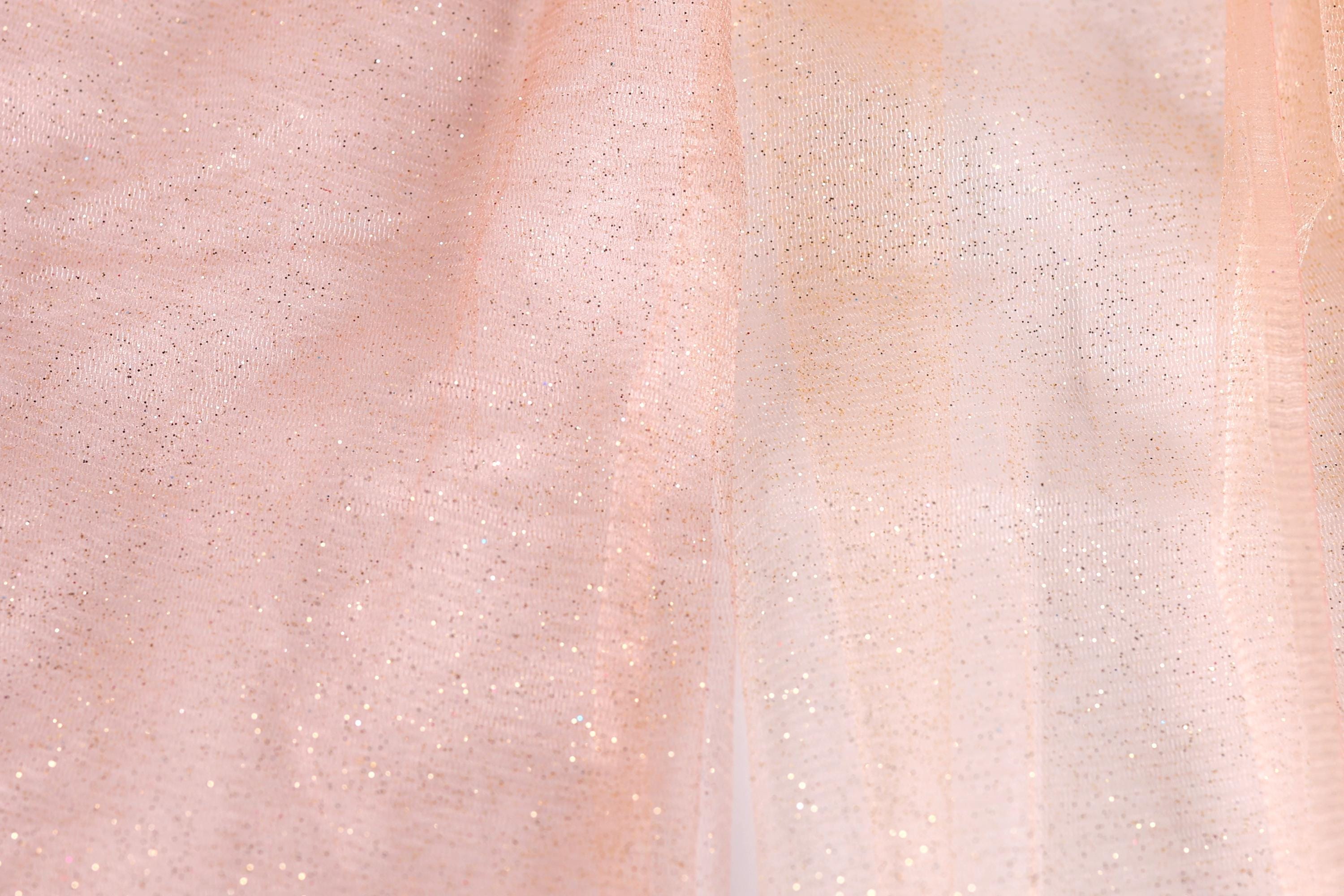 The image is a close-up of a fabric with a pink and white color scheme, featuring a textured and sparkly appearance.
