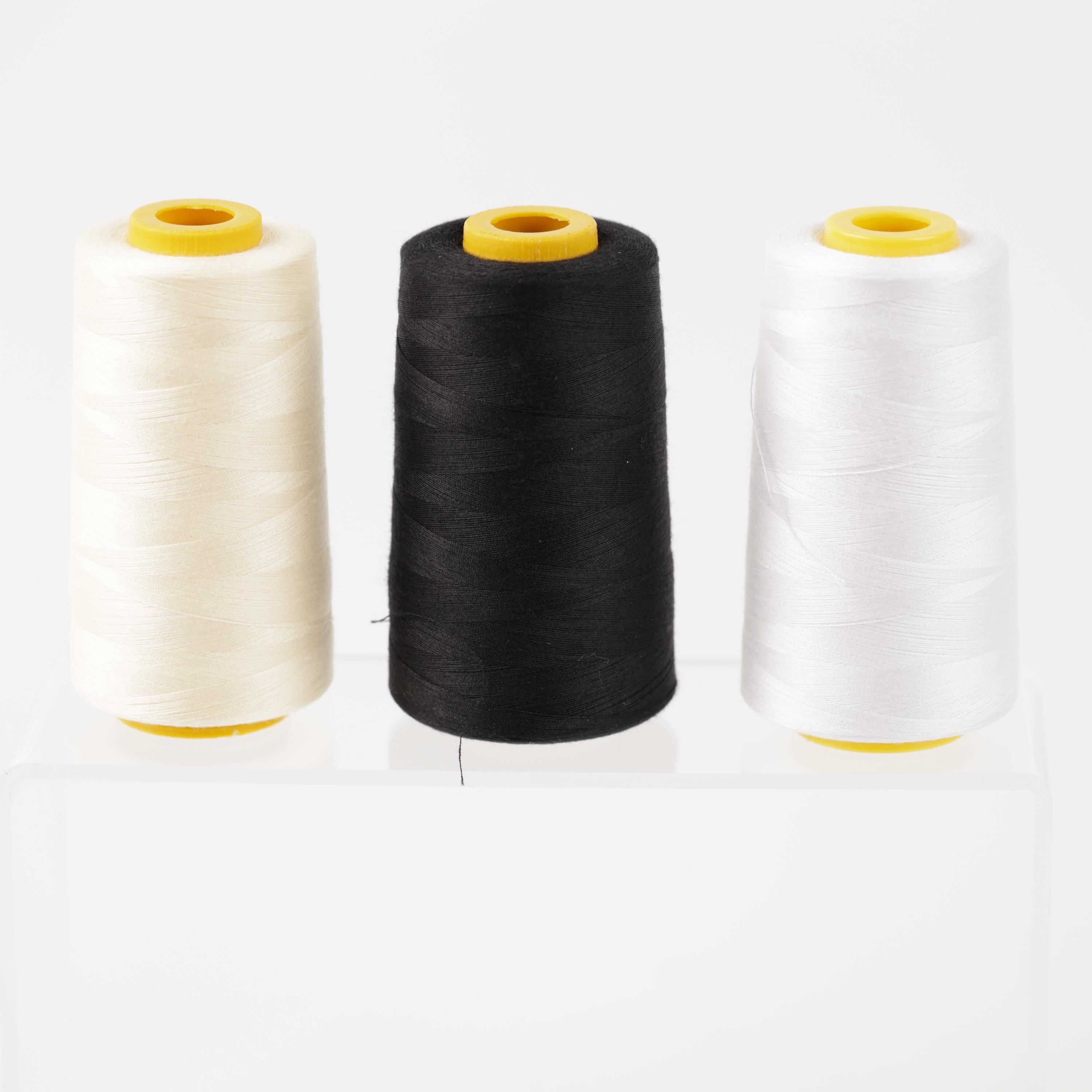 three spools of thread, each with a different color: white, black, and yellow.