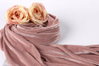 two pink roses resting on a pink velvet fabric.