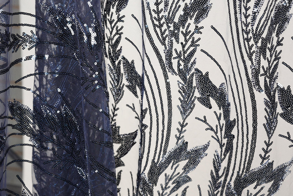 a close-up view of a fabric with a black and white floral pattern, with a dark blue sequin overlay.