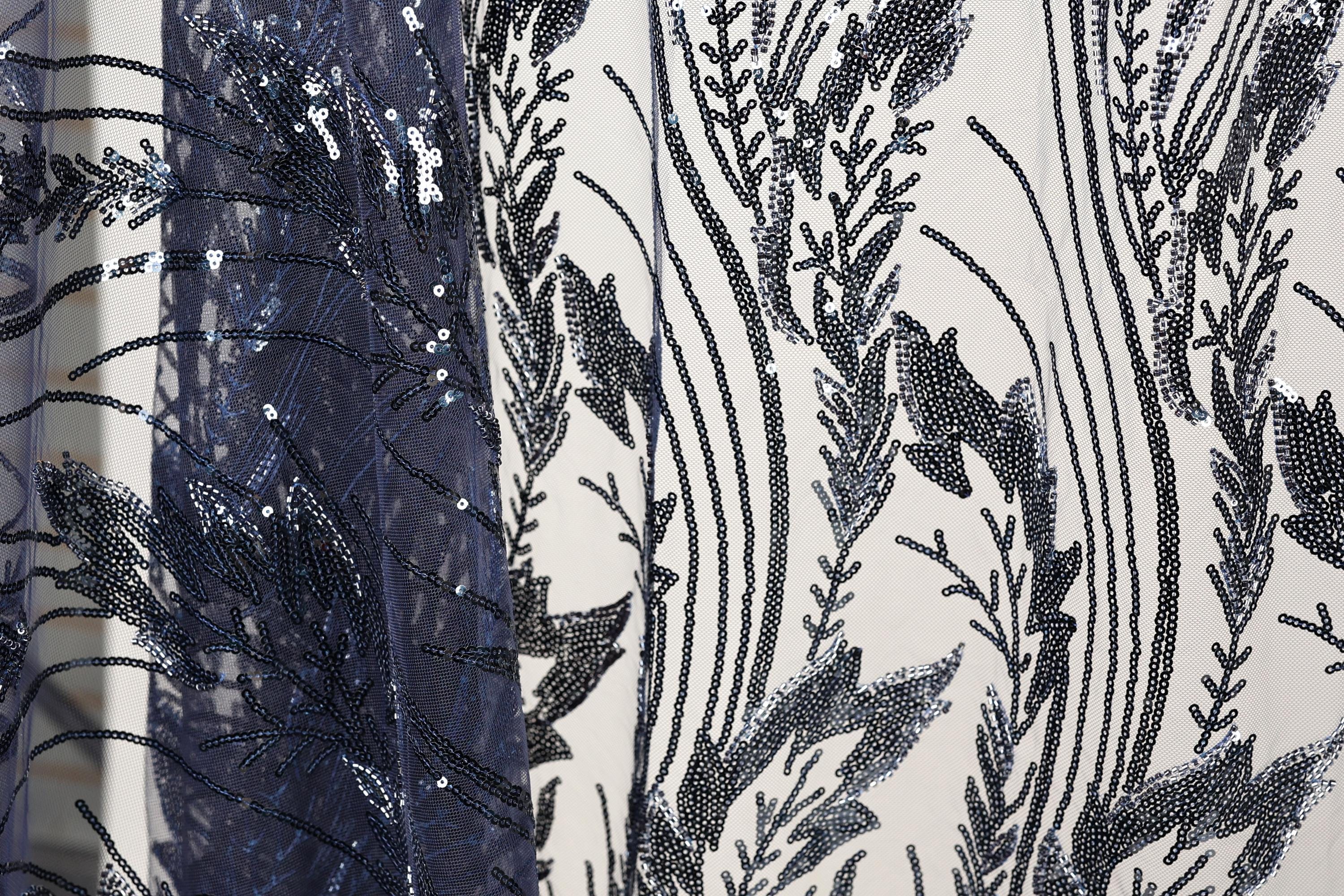 a close-up view of a fabric with a black and white floral pattern, with a dark blue sequin overlay.