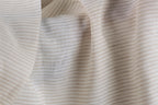 a close-up view of a fabric with horizontal stripes in various shades of beige and white. The fabric appears to be soft and delicate, with a slightly wrinkled texture.