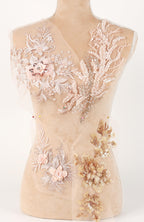 A mannequin torso with intricate, delicate embroidered and beaded designs in shades of pink and gold.