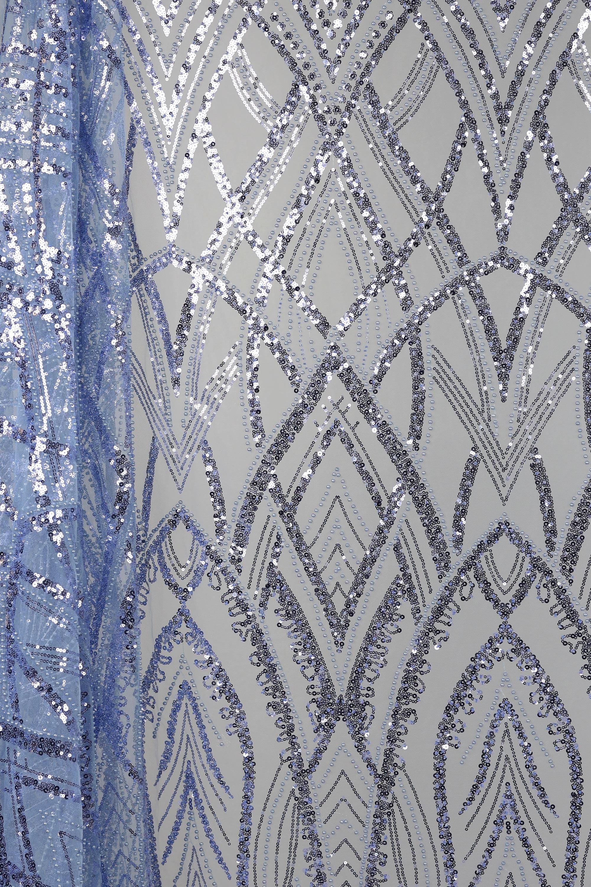 a close-up view of a fabric with a repeating pattern of silver and blue sequin designs. The pattern consists of various diamond shapes and arches, creating a visually striking and intricate design. The fabric appears to be a piece of clothing or textile, with the silver and blue sequins adding a touch of sparkle and elegance to the overall appearance.