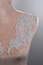 a close-up view of a mannequin torso with intricate white lace embroidery on the shoulder area.